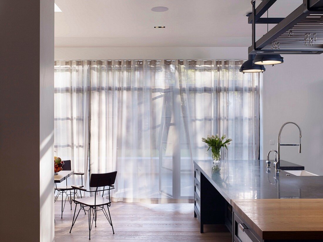 Licht fällt durch Gardinen in moderne Küche mit Kücheninsel