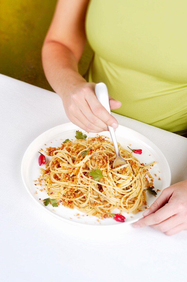 A woman eating spaghetti with anchovies