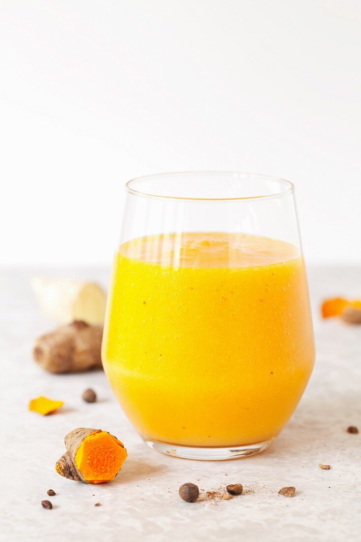 A glass of mango and pineapple smoothie with turmeric
