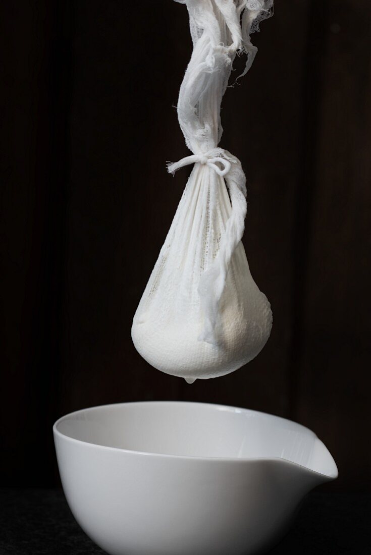 Labneh (Arabian cream cheese) in a cheesecloth over a porcelain bowl