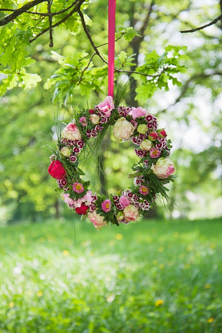 Wreath of flowers hung from branch in summer meadow