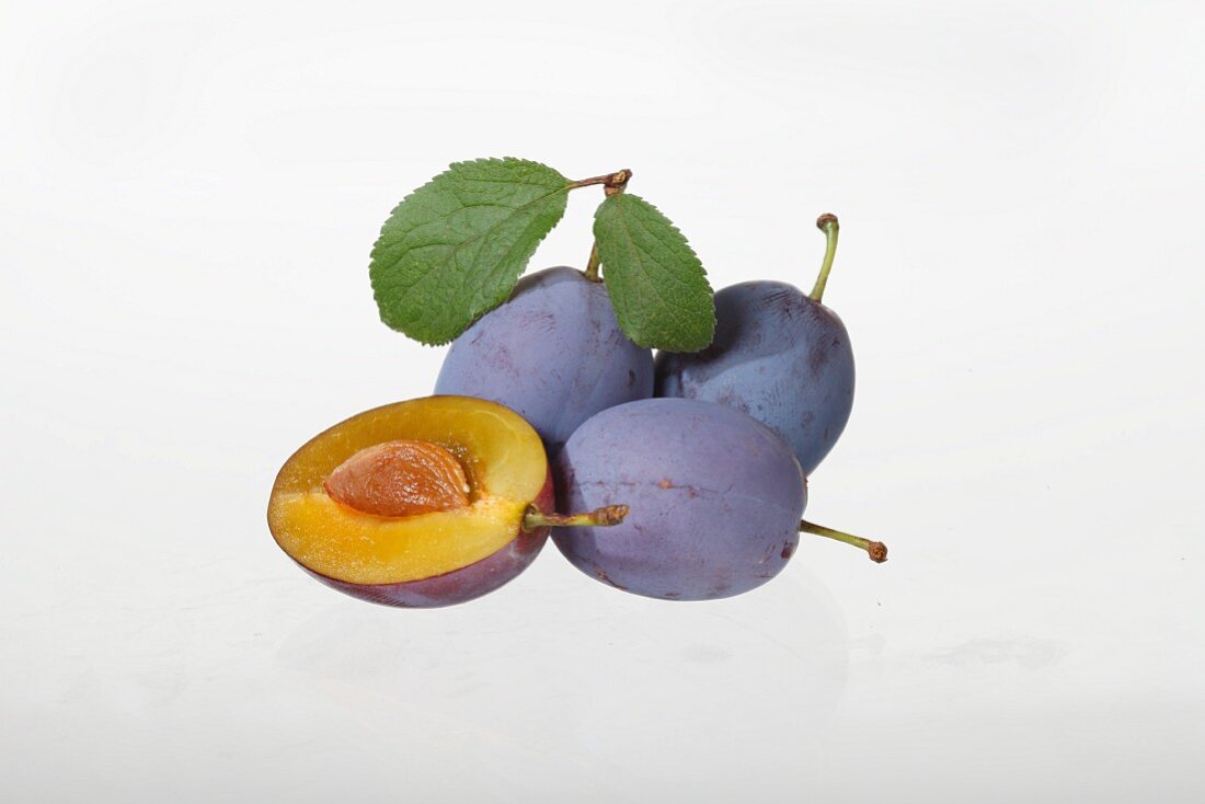 Plums, whole and halved, with leaves