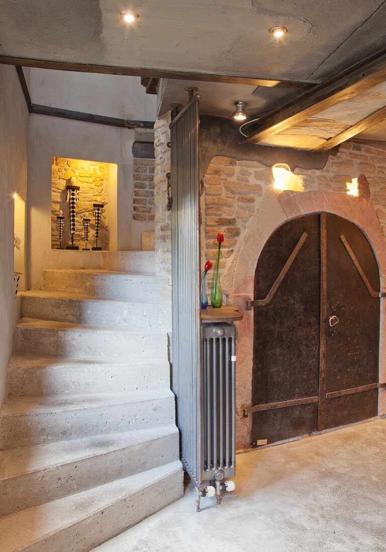 Concrete stairs leading down into cellar with arched door, niches and lighting