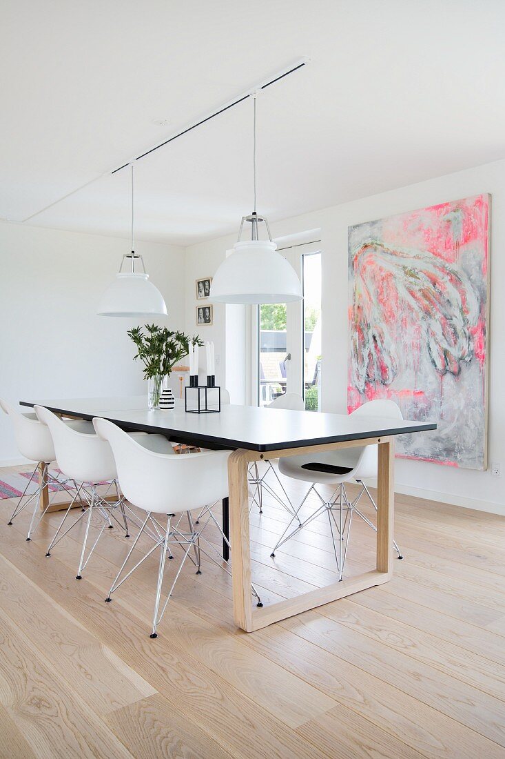 Shell chairs around modern dining table in front of abstract painting