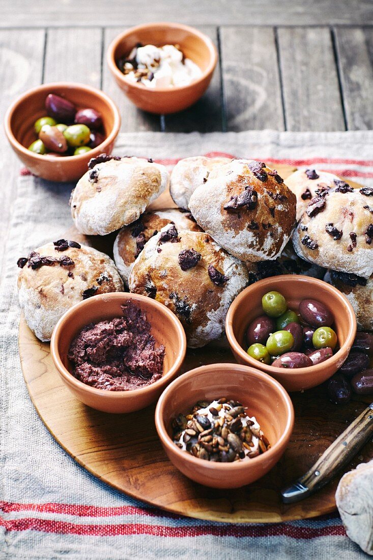 Olive buns next to bowls of olives and tapenade