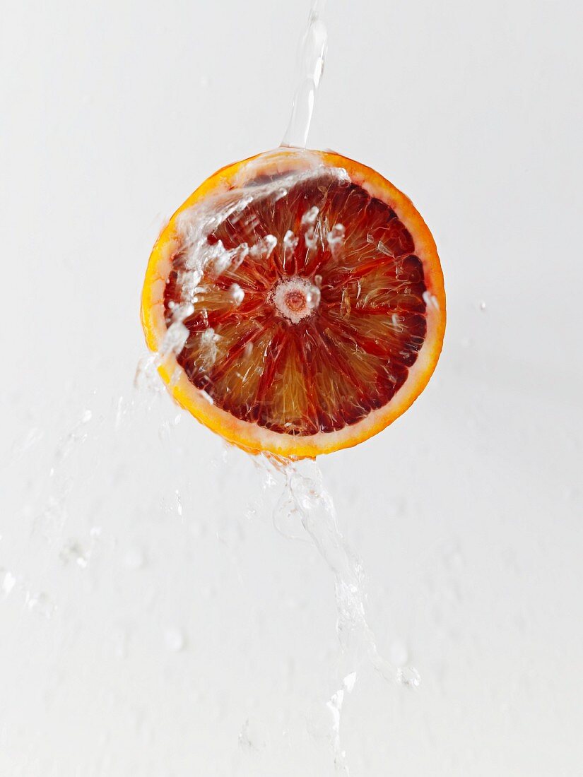 Eine halbe Blutorange mit Wasserstrahl