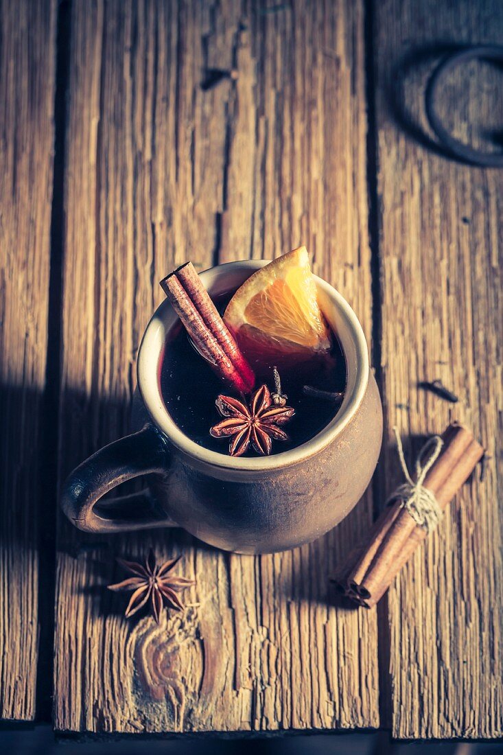 Aromatischer Glühwein mit Gewürzen auf rustikalem Holztisch