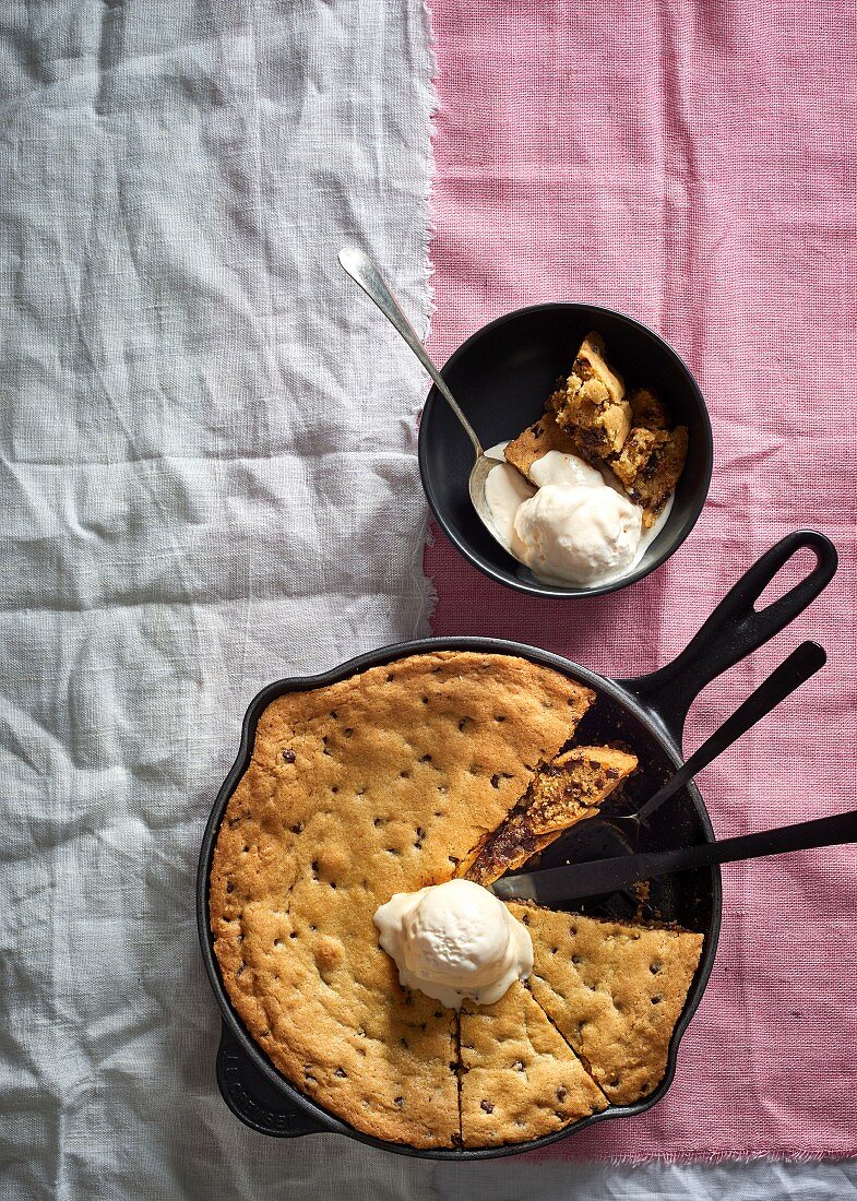 Chocolate chip cookies dough served from a frying pan with vanilla ice cream