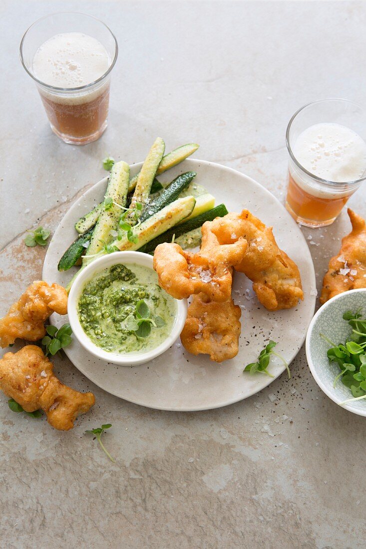 Beer-battered fish nuggets with fried baby courgettes and pesto and sour cream sauce