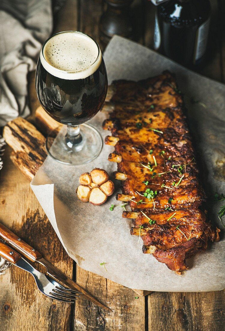 Roasted pork ribs with garlic, rosemary and glass of dark beer