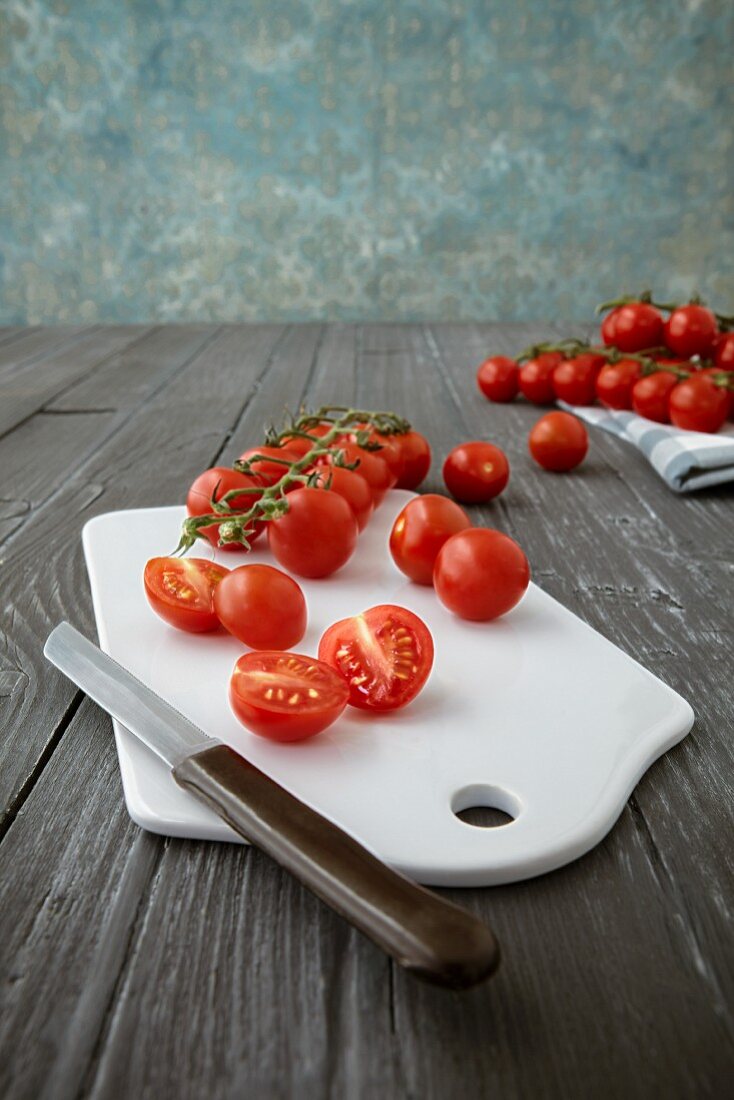 Cherry tomatoes on a chopping board, whole and halved