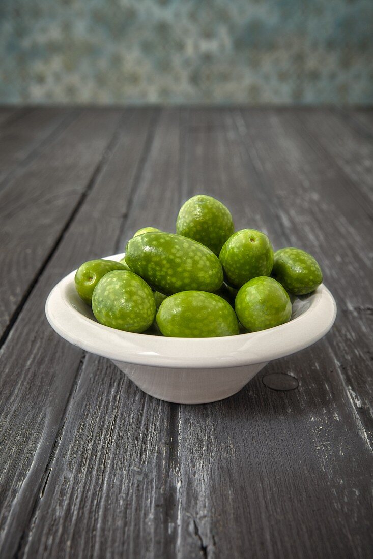 Olives (from Arbosana, Chile) in a bowl on a wooden surface