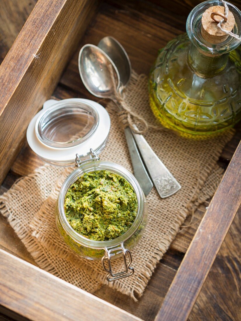 Vegan coriander and parsley pesto in a small jar on a wooden surface