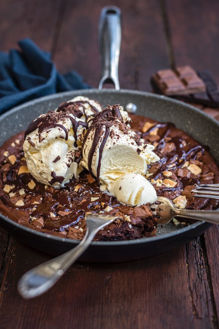 A brownie with vanilla ice cream in a frying pan
