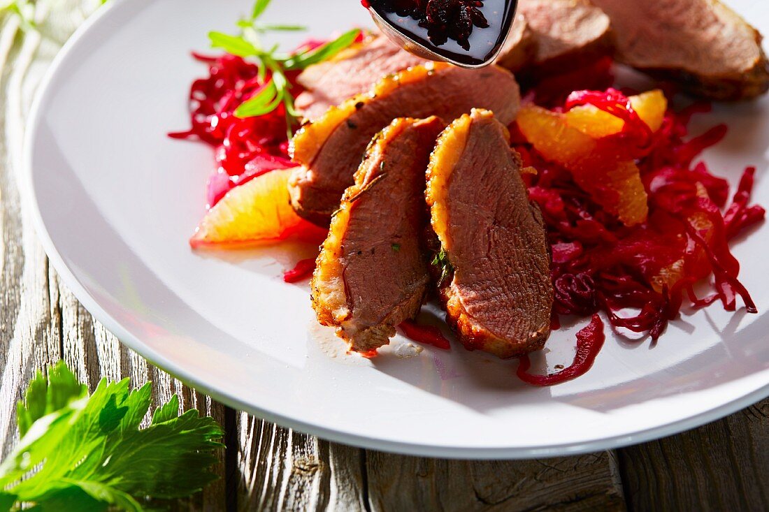 Duck breast with orange fillets on a bed of red cabbage (close-up)