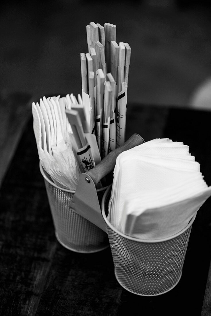 Essstäbchen und Servietten in Metallgefässen auf Restauranttisch