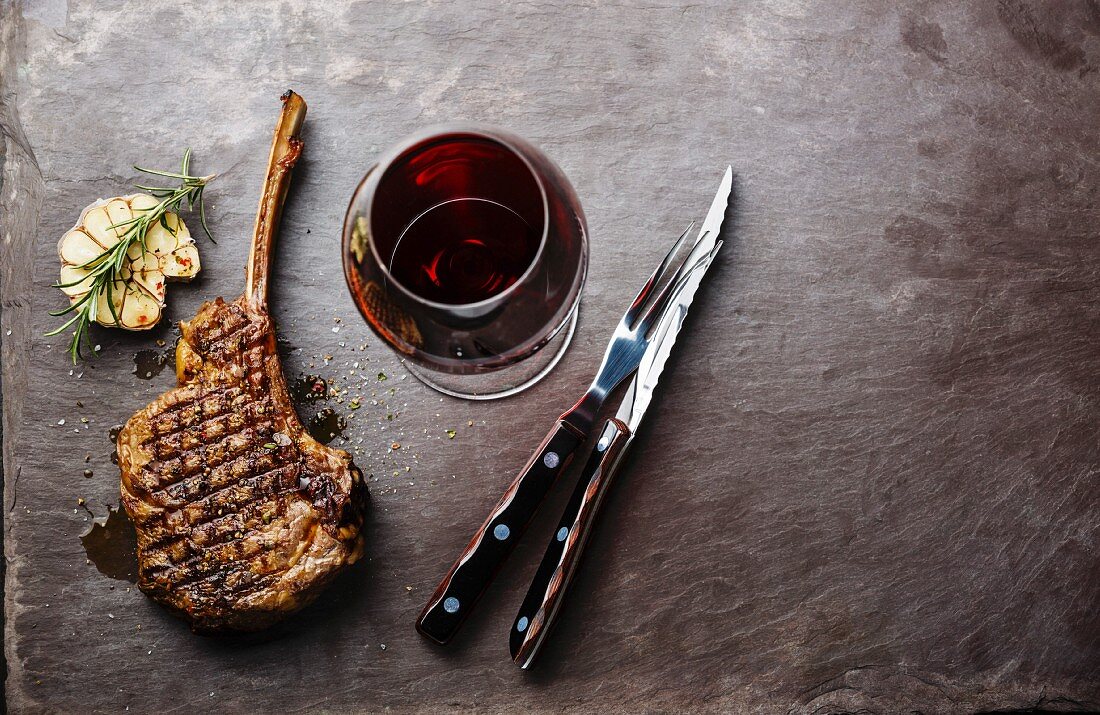 Grilled beef barbecue Veal rib Steak on bone and wine on stone slate background