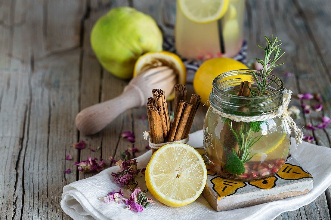 Limonade mit frischer Zitrone, Minze, Zimt und Quitte auf Holzuntergrund