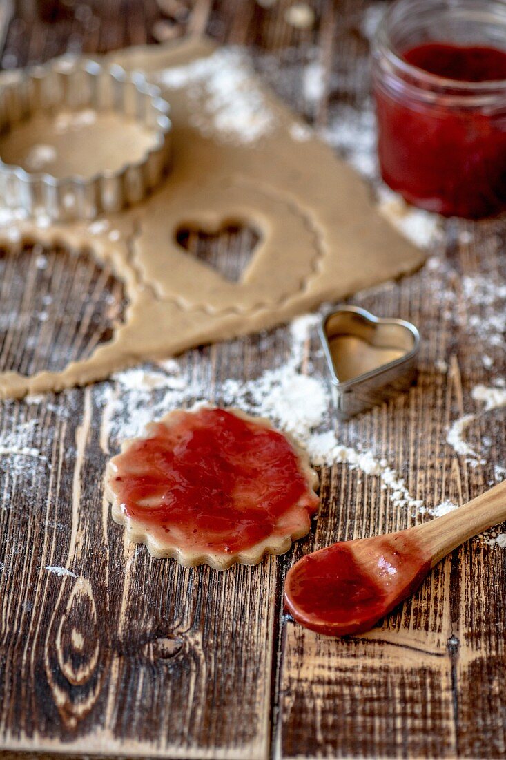 Jam being spread onto unbaked vegan shortbread biscuits