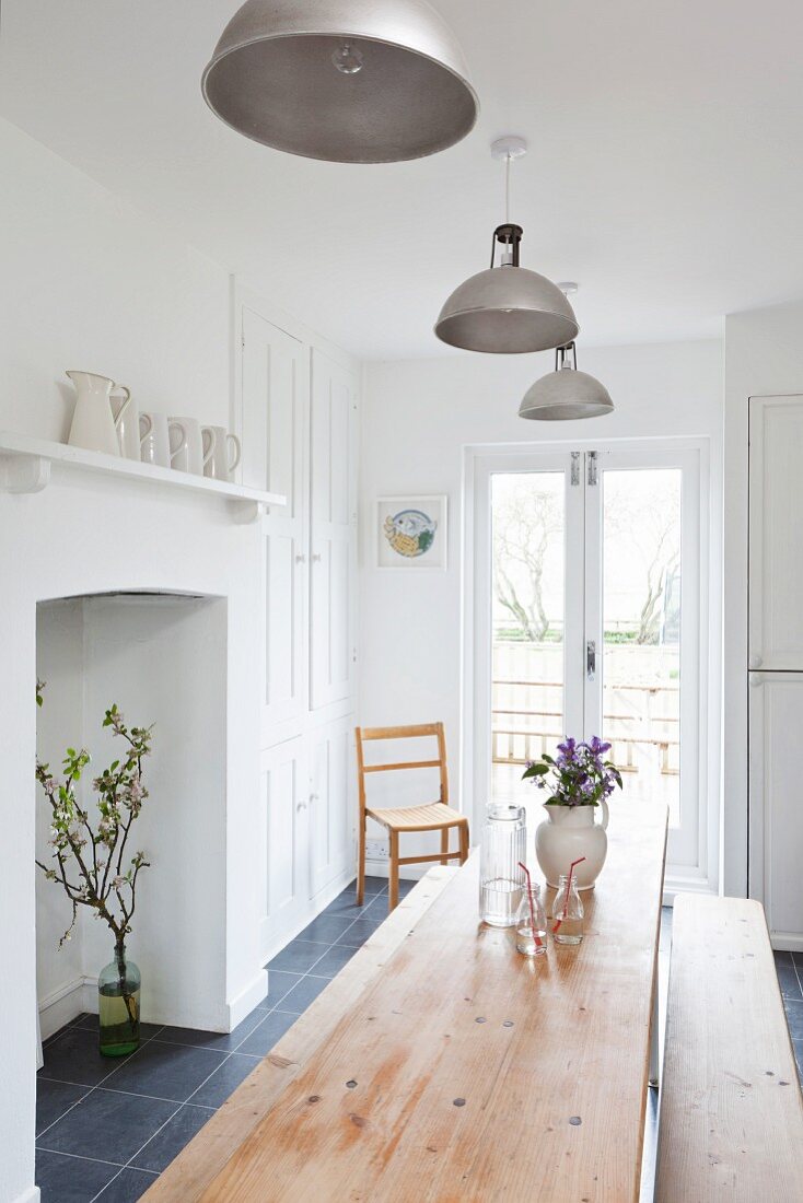 Wooden dining table below metal pendant lamps