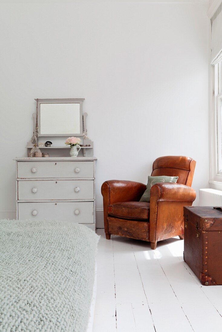 Brown leather armchair in corner of white bedroom