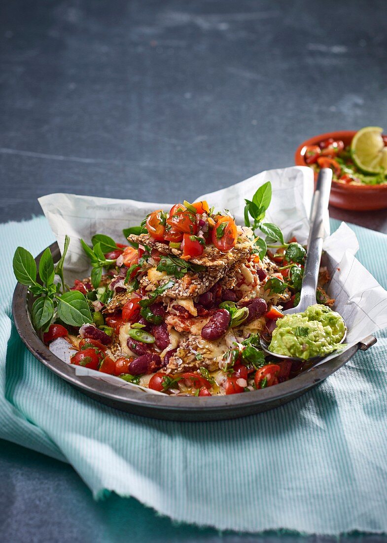 Cracker nachos with tomato, kidney beans, mozzarella and guacamole