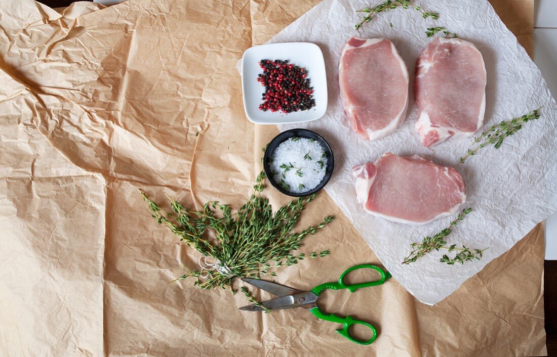 Raw pork chops with herbs and spices (seen from above)