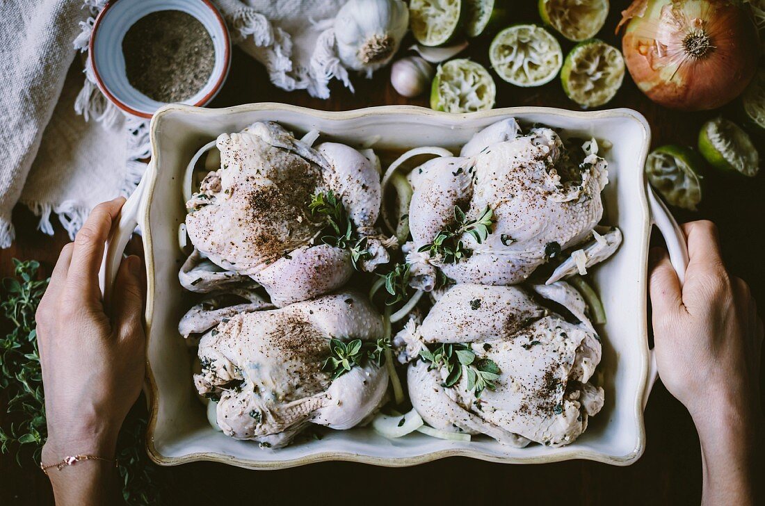 Four seasoned game hens in a casserole pan