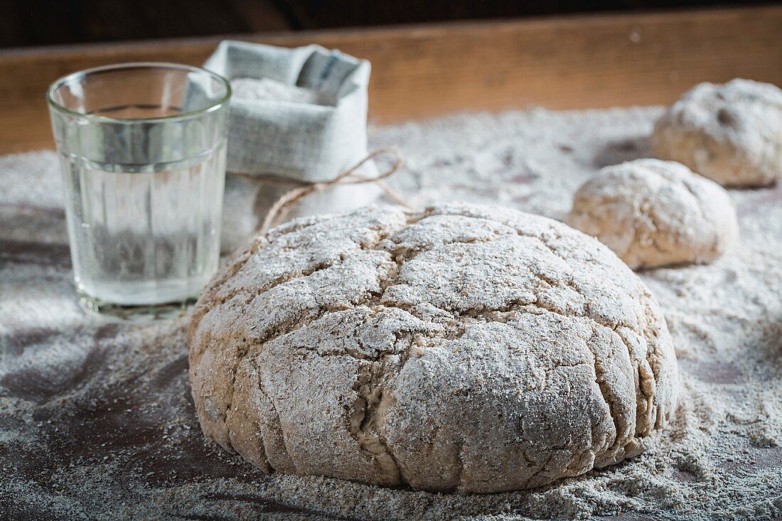 Unbaked loaves of bread and bread rolls with ingredients and flour