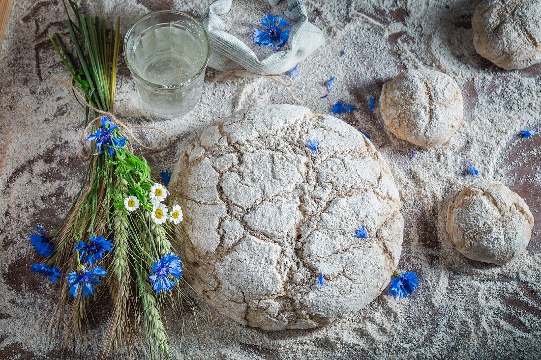 Ungebackene Brötchen und Brot mit Mehl, Wasser und Getreideähren