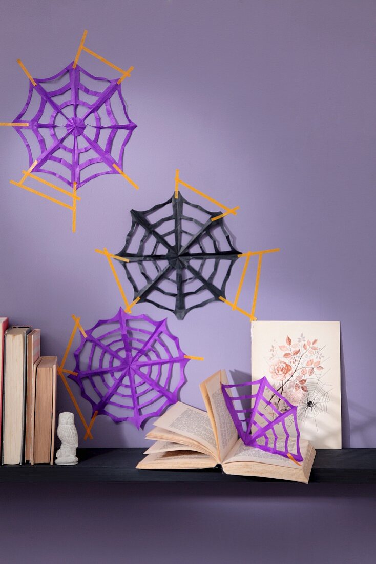 Hand-made paper spiders' webs on purple wall