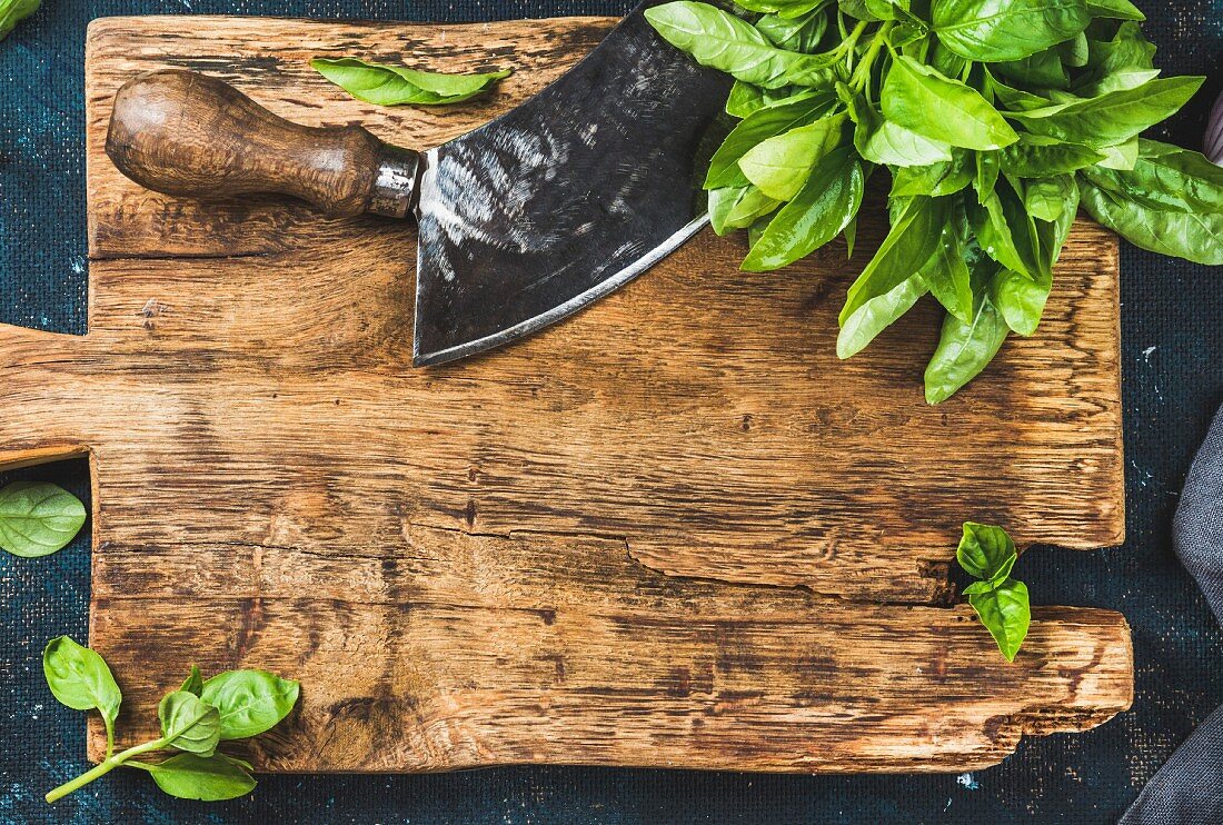 Fresh green basil and vintage herb chopper on rustic wooden bord