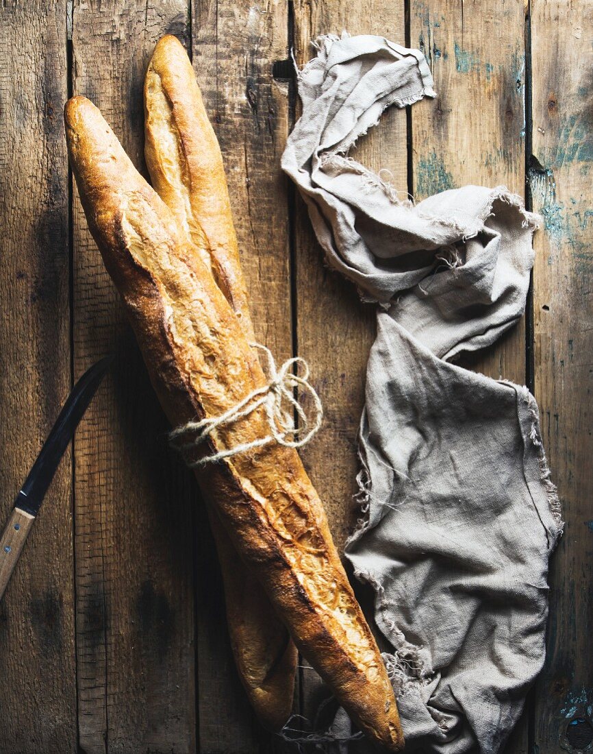 Two French baguettes on a rustic wooden surface