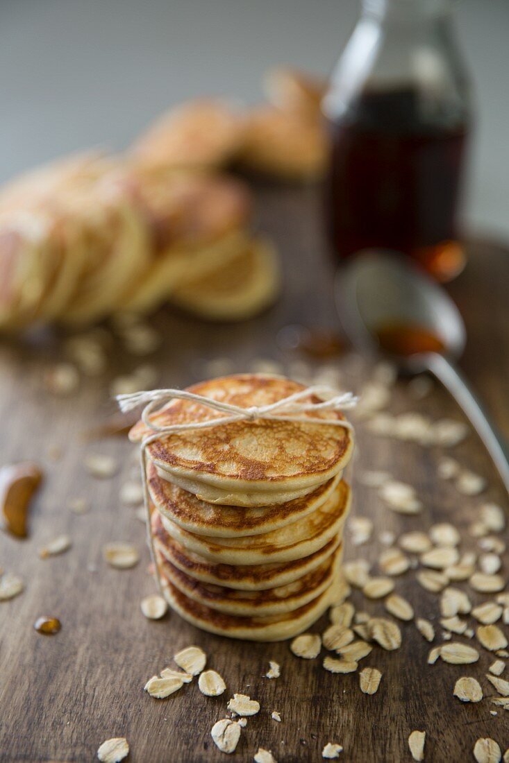 A stack of mini pancakes with oats and maple syrup
