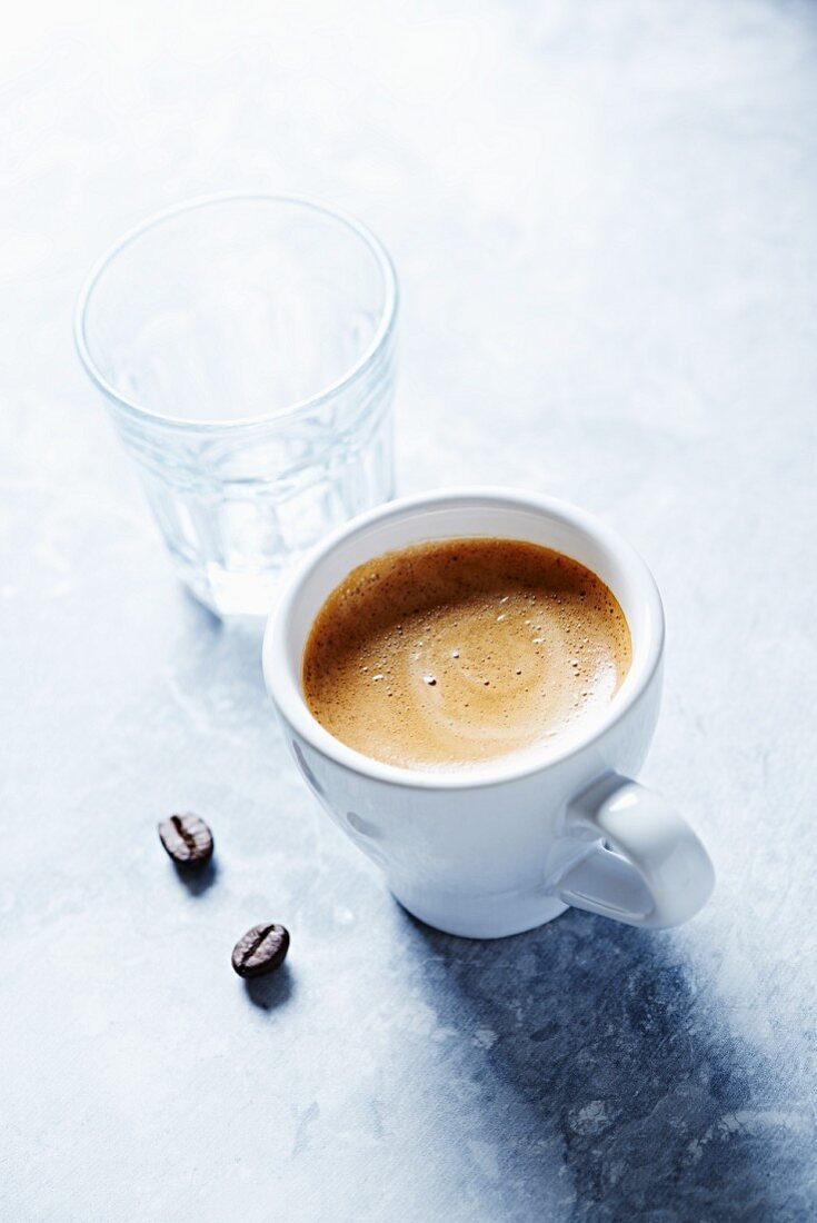 Tasse Espresso, Wasserglas und Kaffeebohnen