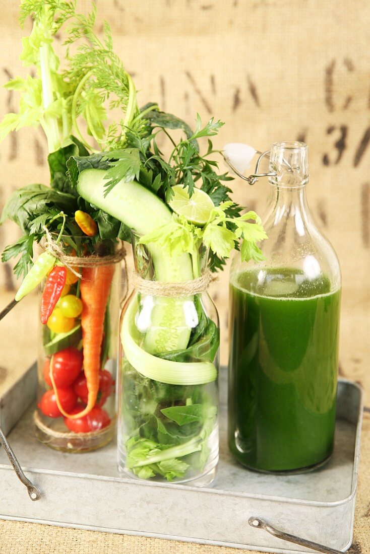 Healthy mixed vegetable juice with ingredients in glasses and a bottle
