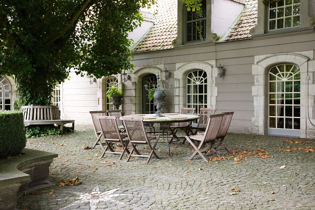 Sitzplatz auf dem gepflasterten Hof vor klassischem Gebäude