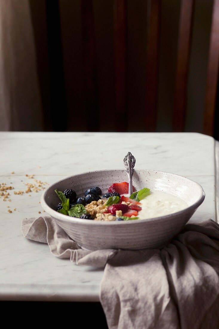 Joghurt mit frischen Beeren und Granola in einem Schälchen