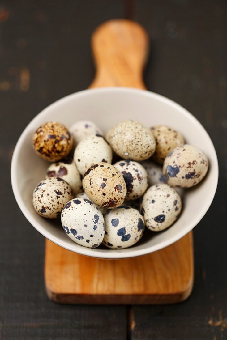 Quail eggs in a bowl on a chopping board