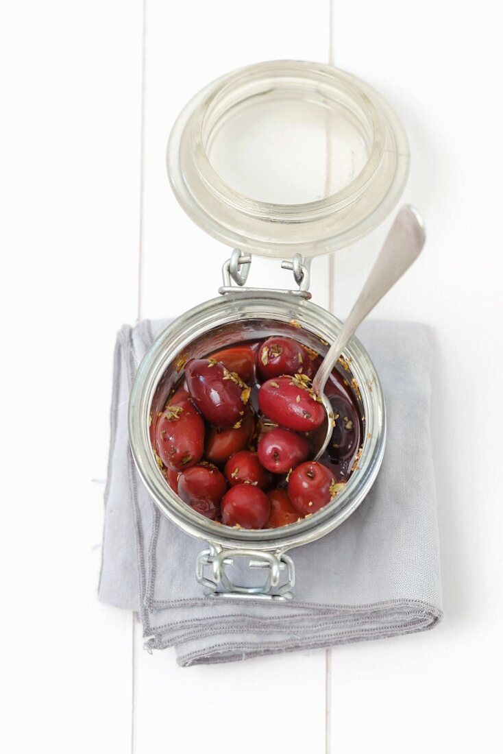 Pickled kalamata olives with oregano in a glass jar