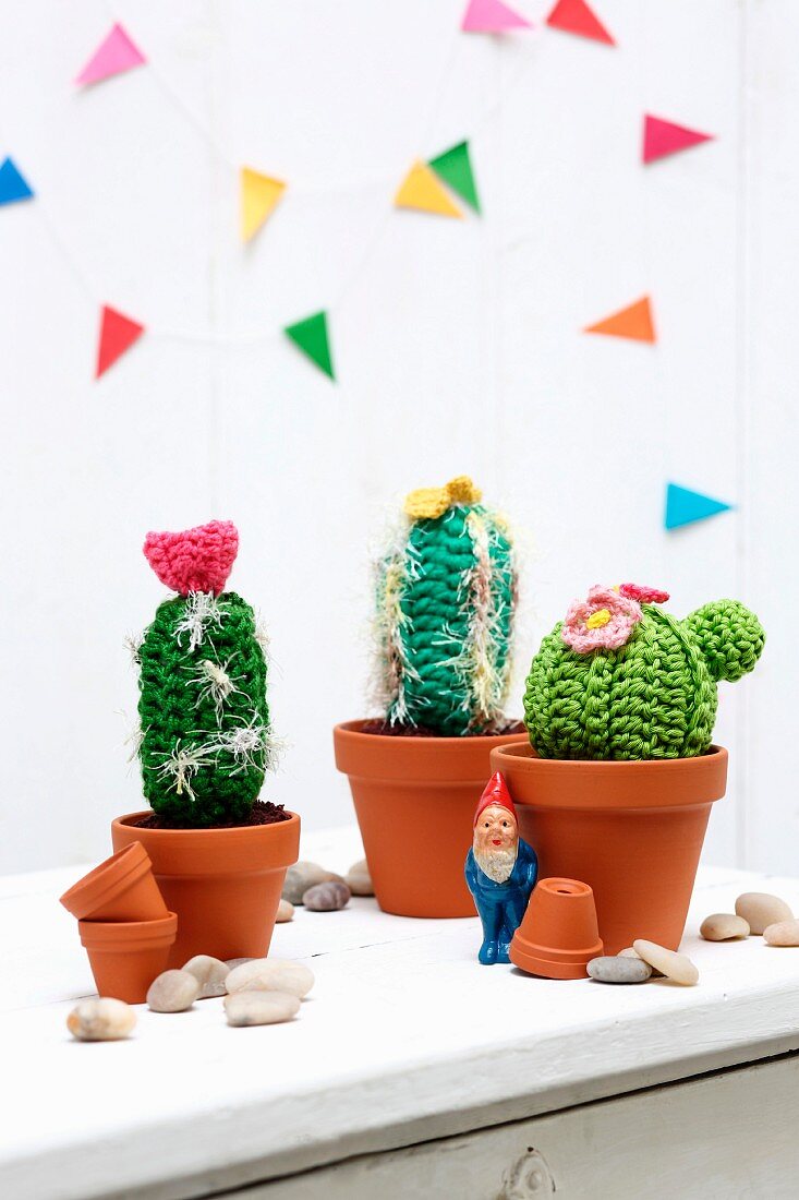 Garden gnome amongst crocheted cacti in terracotta pots