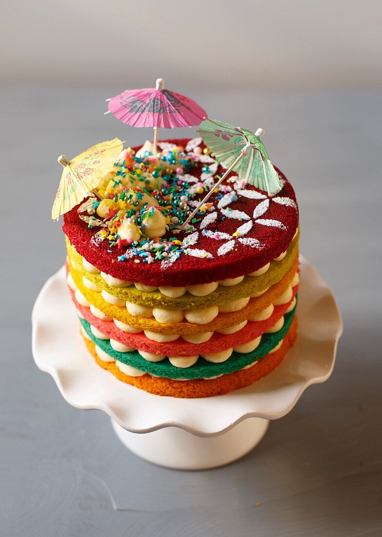 A rainbow cake with cocktail umbrellas