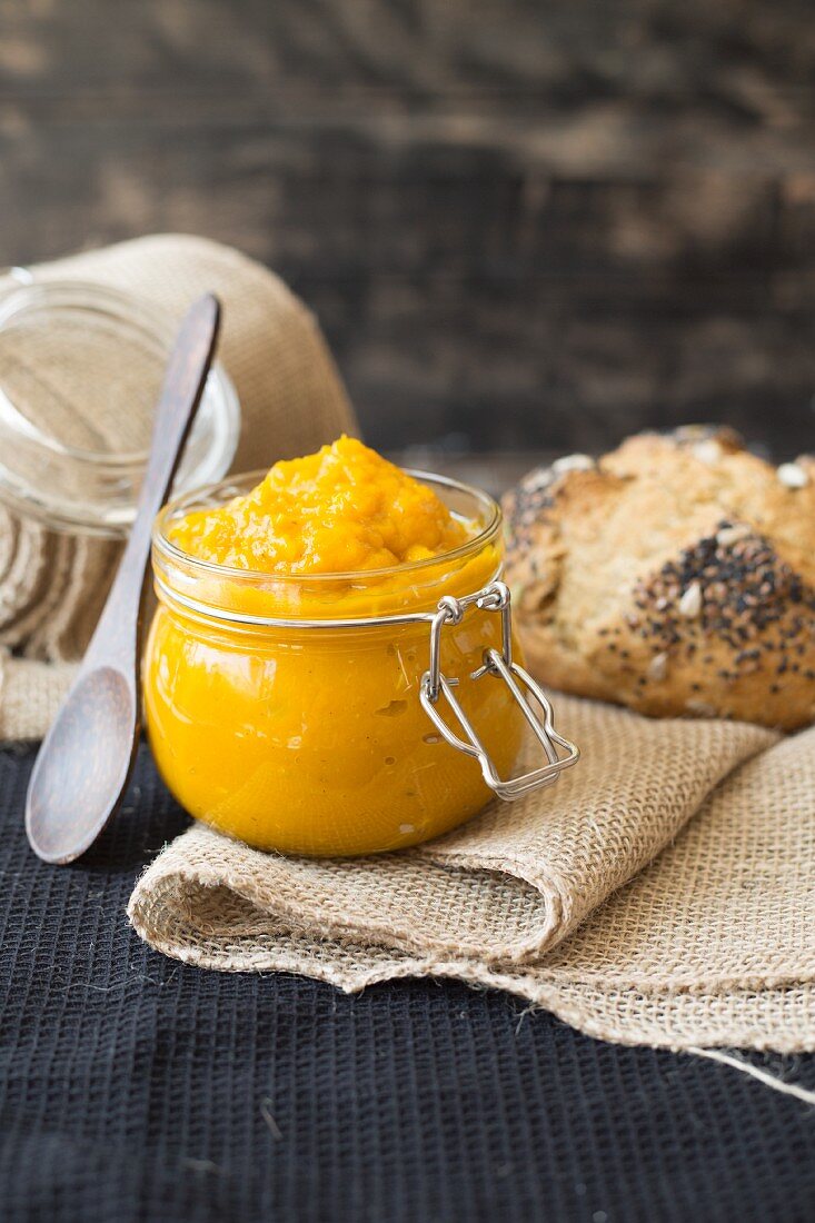 Pumpkin dip in a glass jar in front of a loaf of sour dough bread