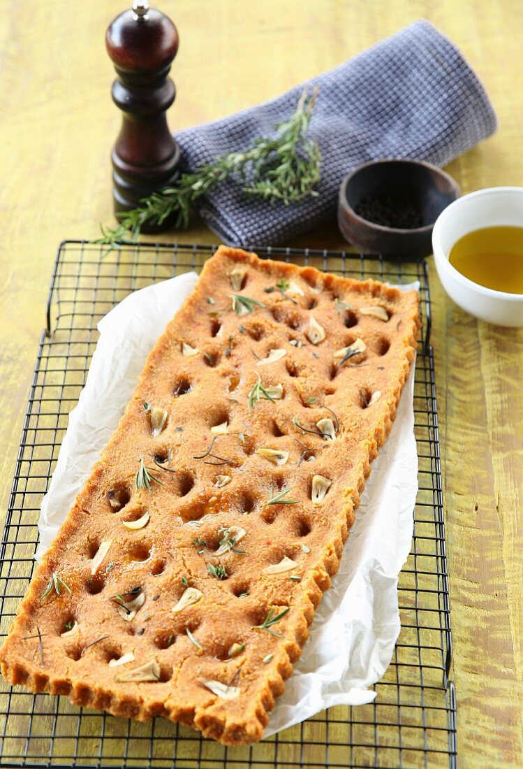 Vegan focaccia with dried tomatoes, garlic and herbs on a cooling rack