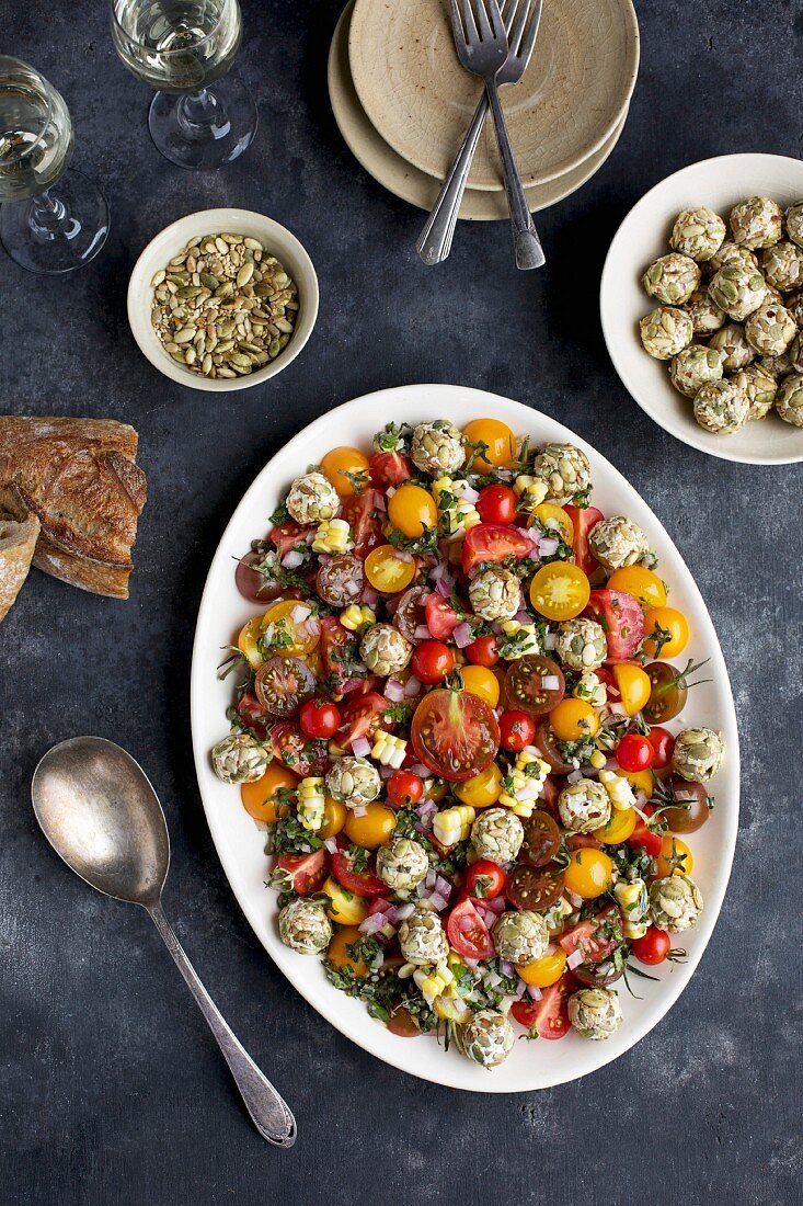 Cherry tomato salad and goats' cheese balls with toasted seeds served with white wine and bread