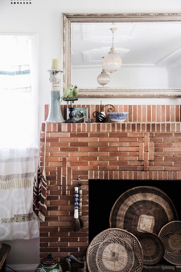 Mirror over open brick fireplace with wicker bowls