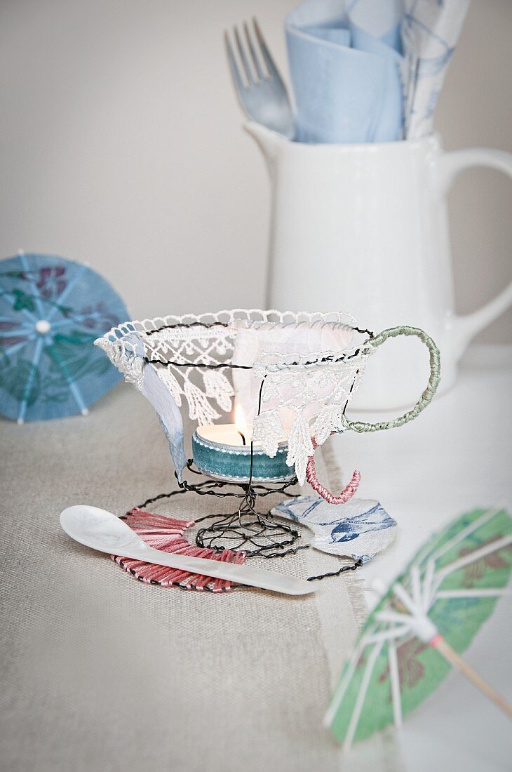 Teacup-shaped tealight holder hand-made from wire and lace on table
