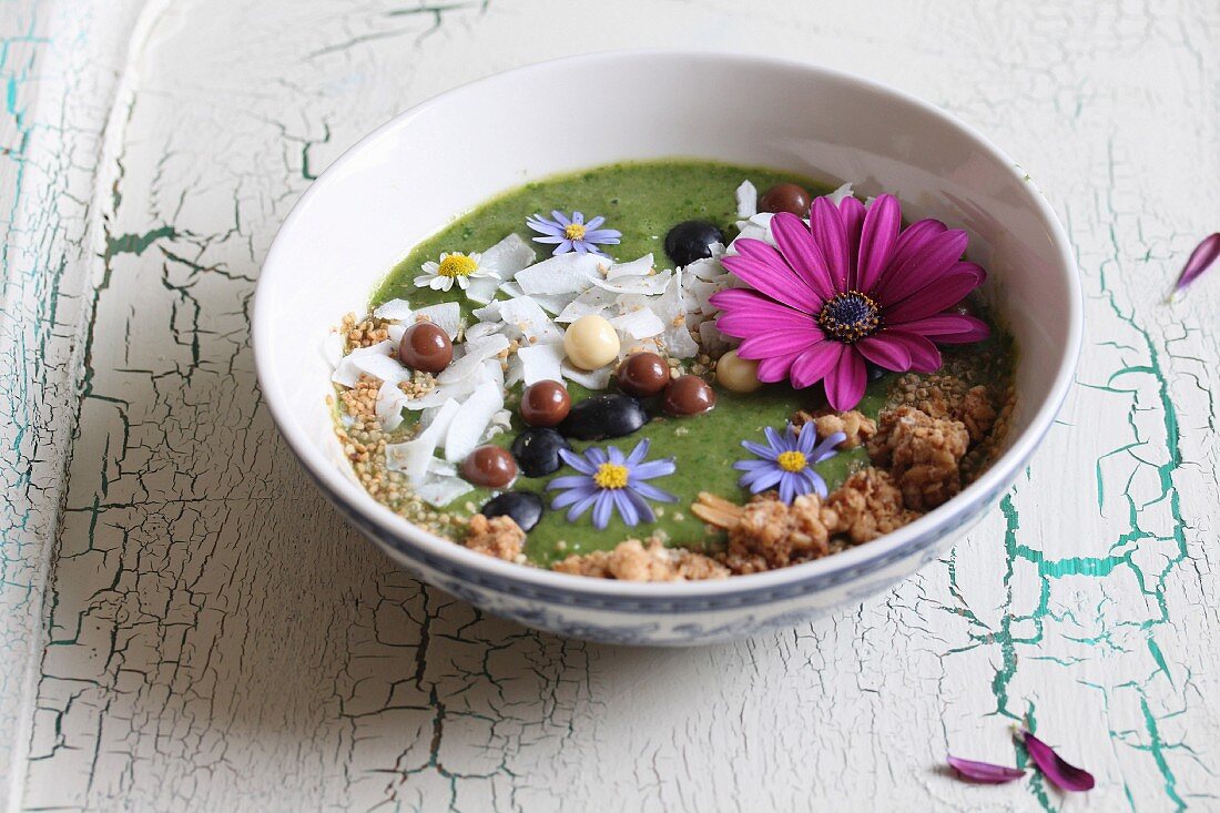 A green smoothie bowl with edible flowers and coconut