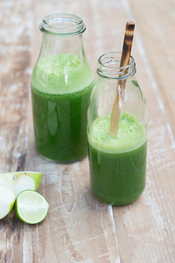 Veganer grüner Smoothie mit Apfel und Limette in Glasflaschen