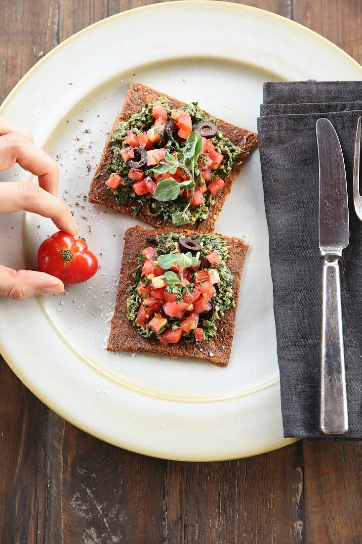 Vegan bruschetta with tomatoes and olives on a plate (seen from above)